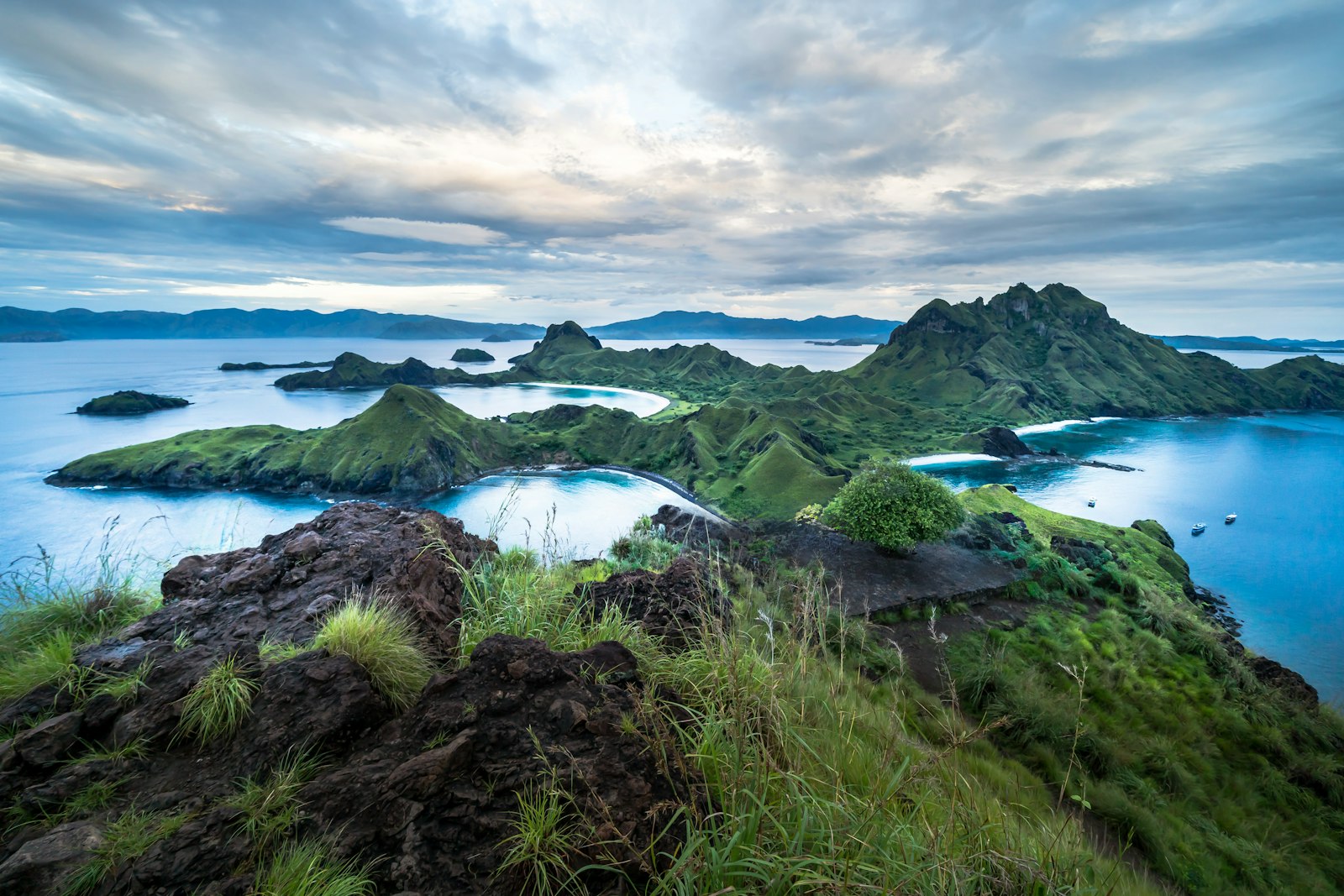 Green islands with blue water under cloudy sky