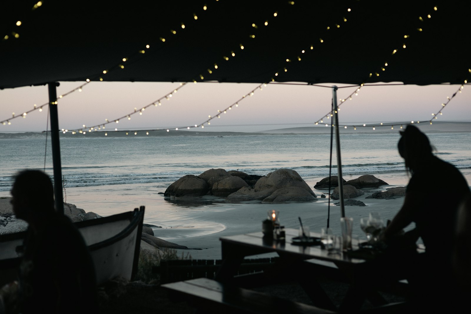 A couple of people sitting at a table near the ocean